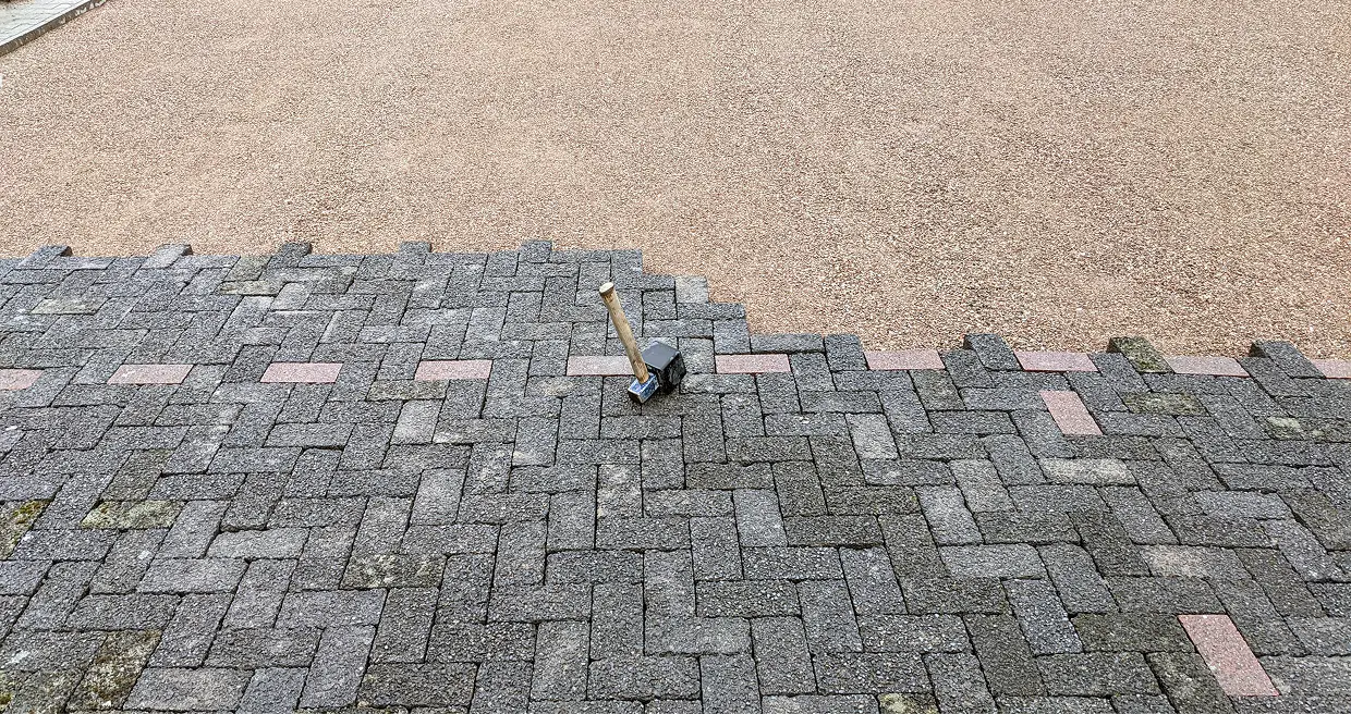A baseball bat laying on the ground in front of a brick wall.