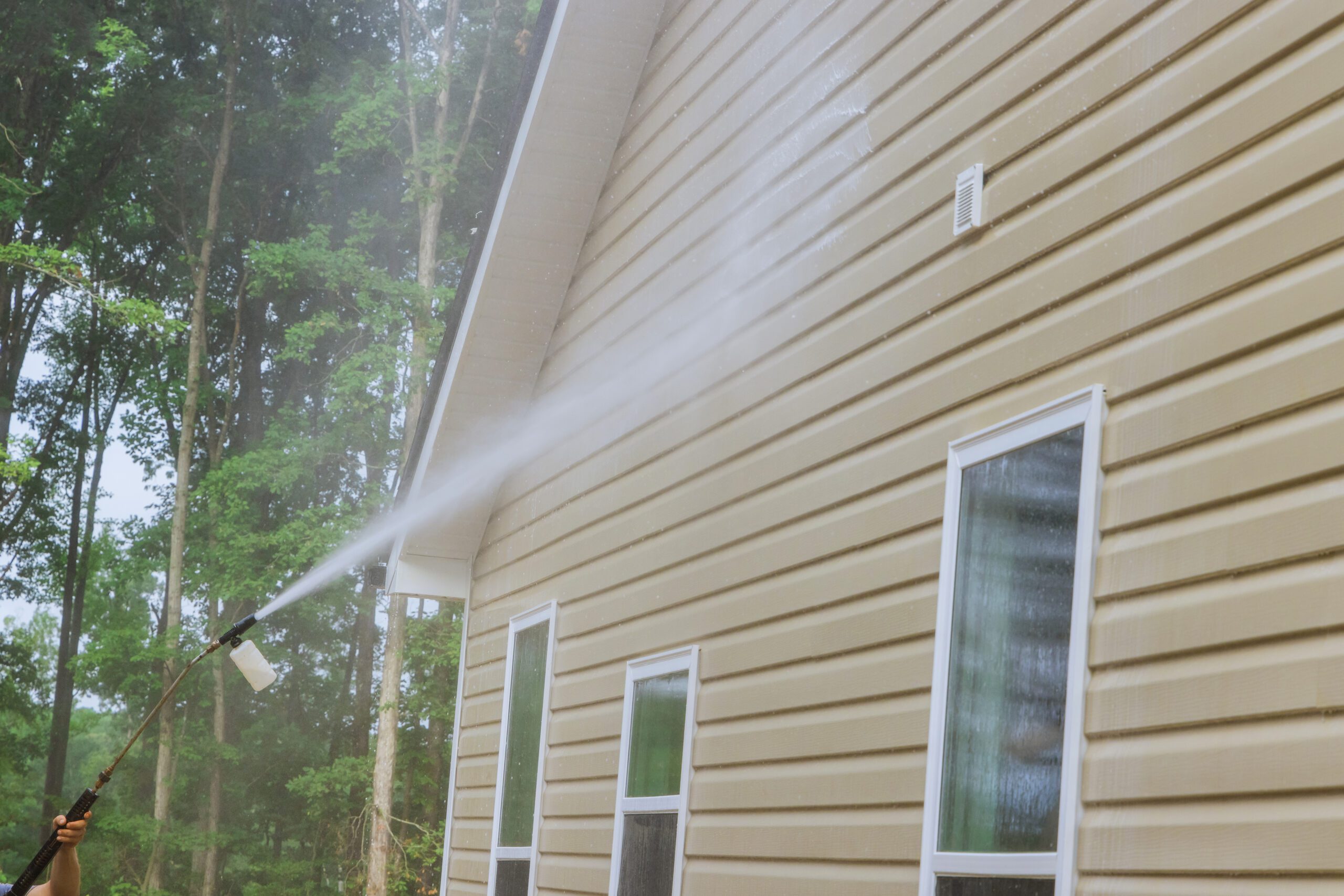 Cleaning and maintenance service for washing the house and maintaining the home with a high-pressure spray nozzle with soap cleaner and water A house with a hose spraying water on it.
