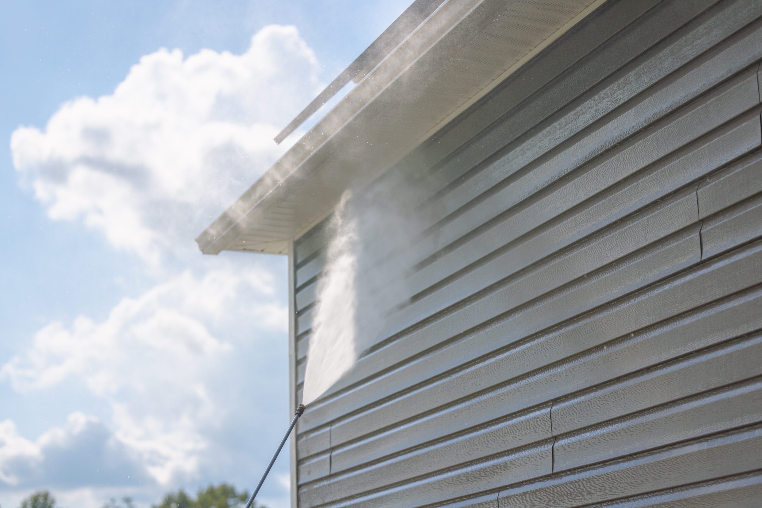 A house with a power washer spraying water on it.