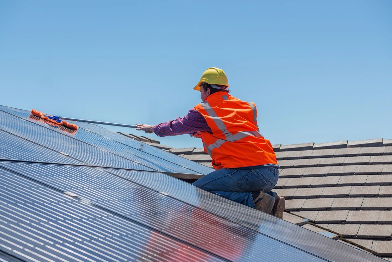 fm=f_V8aOq6n A man in an orange vest is working on solar panels.