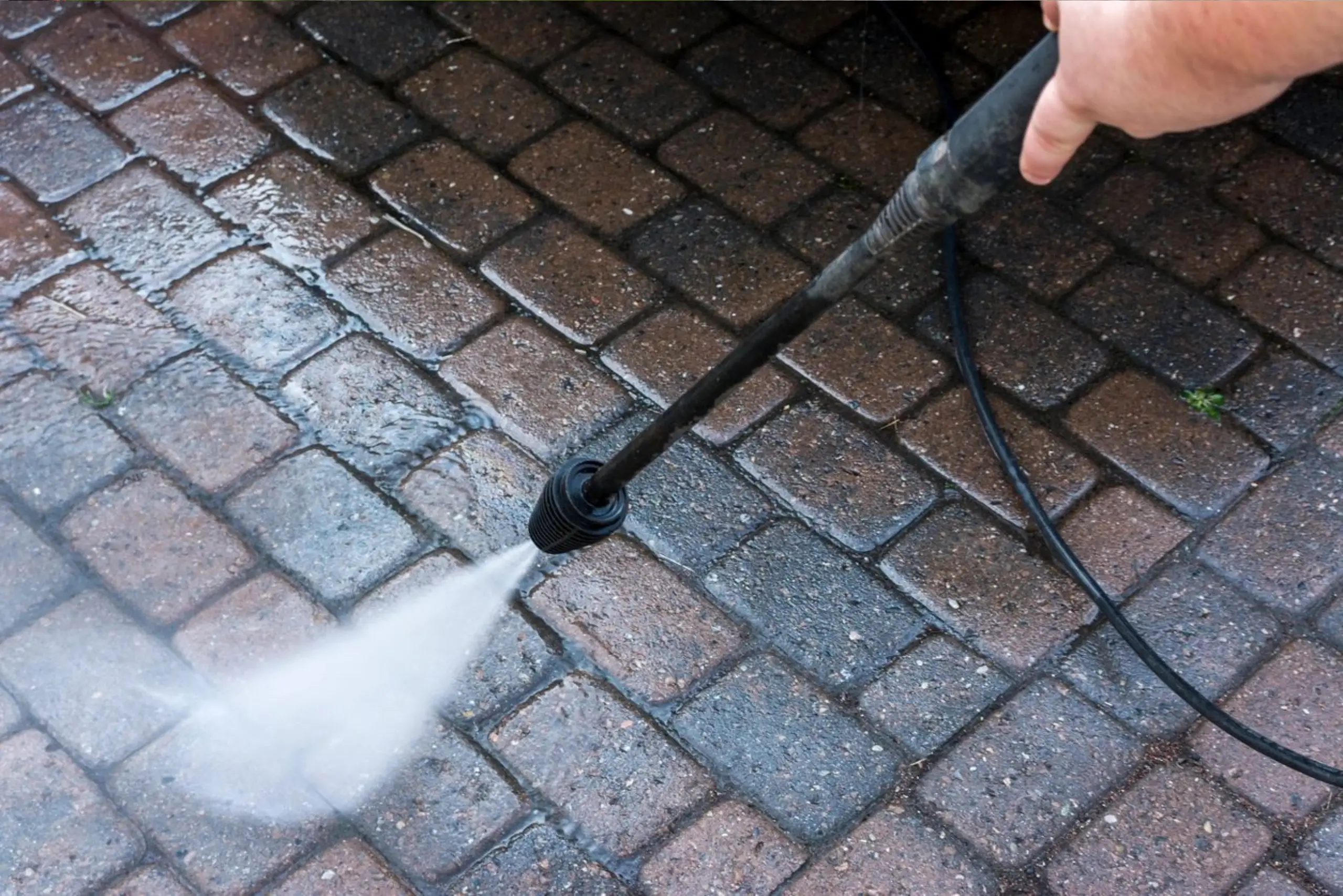A person using a power washer on the ground.